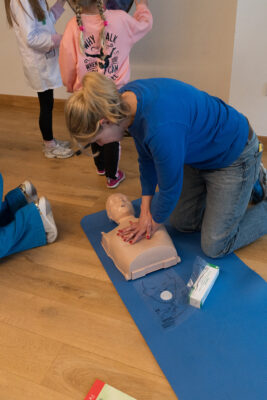 a woman in a blue shirt doing CPR on a dummy in a CPR and AED training course in Edinburgh